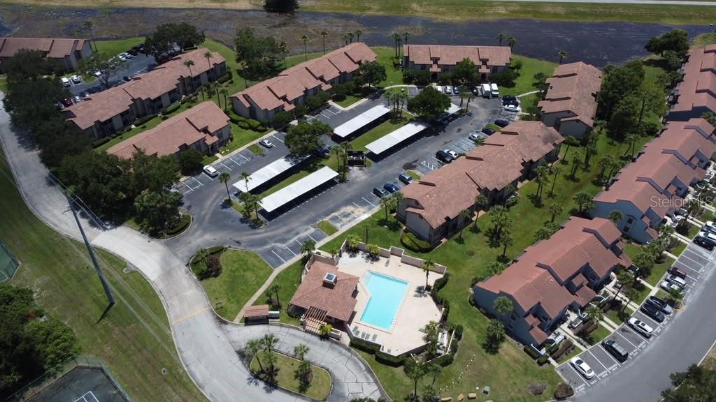 An aerial view shows a multi-building apartment complex with a swimming pool and parking — 4807 NORMANDY PLACE UNIT 202, ORLANDO, FL