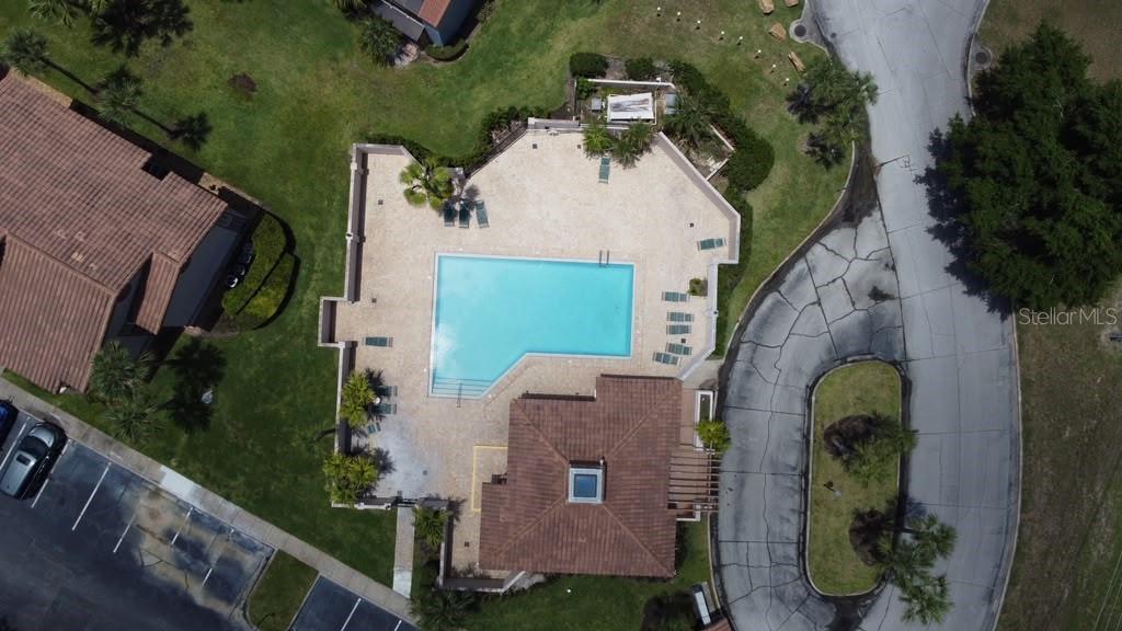 An aerial view shows a community swimming pool with a surrounding deck and clubhouse building — 4807 NORMANDY PLACE UNIT 202, ORLANDO, FL