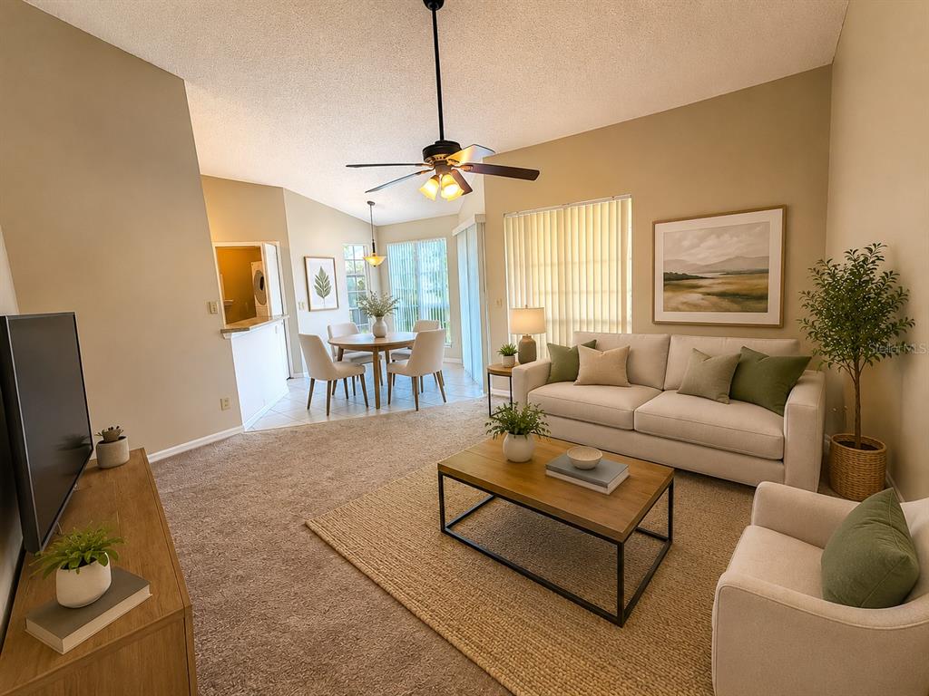 A living room with a beige sofa, coffee table, and dining area with a ceiling fan — 4807 NORMANDY PLACE UNIT 202, ORLANDO, FL