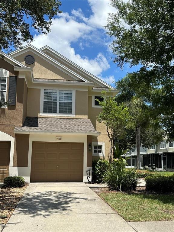 A two-story tan townhouse features a single-car garage and a concrete driveway — 7163 83RD DRIVE E, BRADENTON, FL