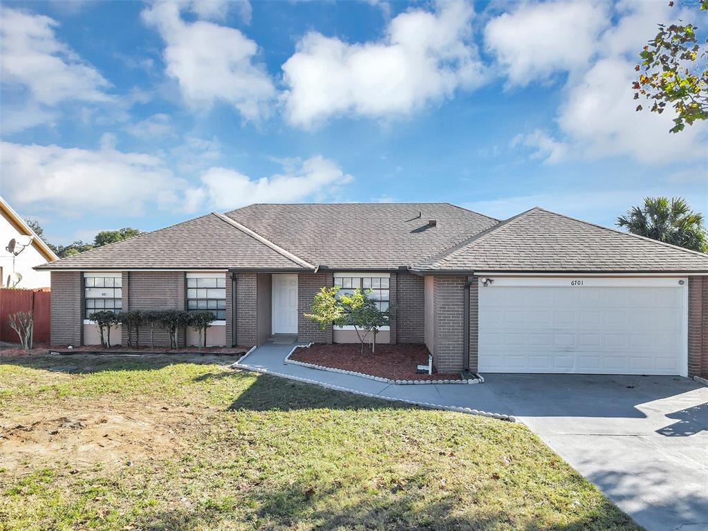 A single-story brick house with a two-car garage and a front walkway — 6701 MERLIN COURT, ORLANDO, FL