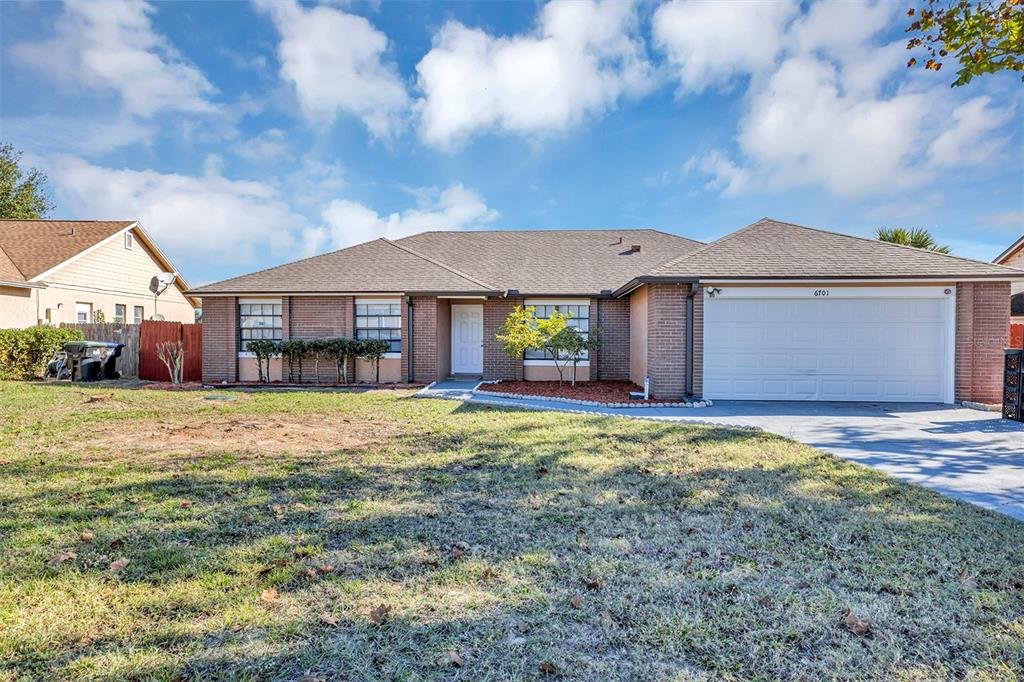 A single-story brick house with a white garage door and a front lawn — 6701 MERLIN COURT, ORLANDO, FL