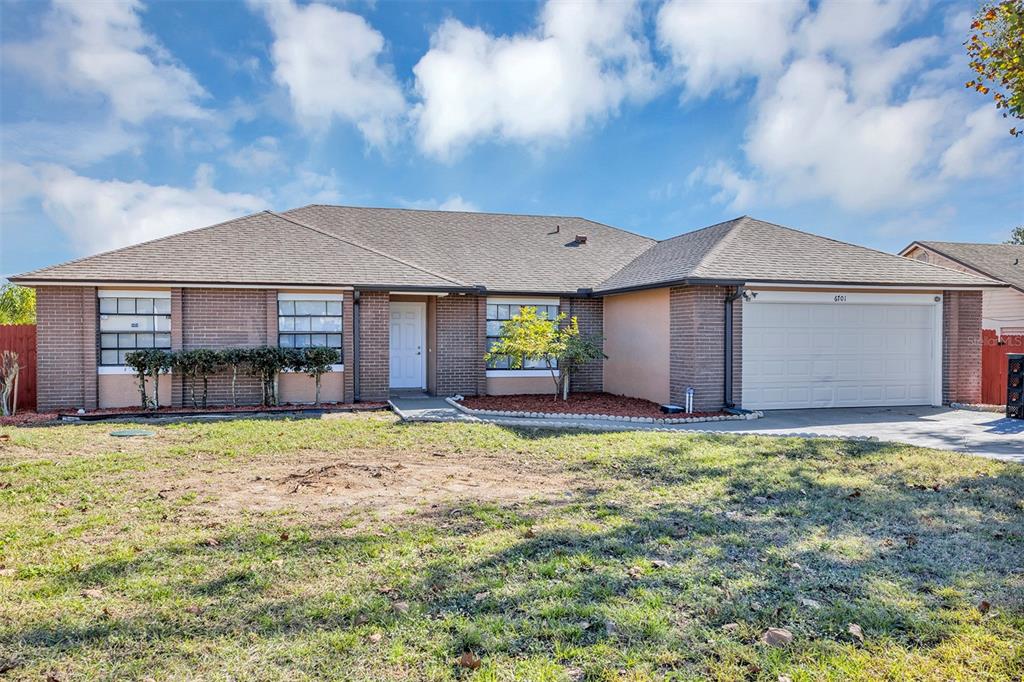 A single-story brick house with a two-car garage and a large front lawn — 6701 MERLIN COURT, ORLANDO, FL