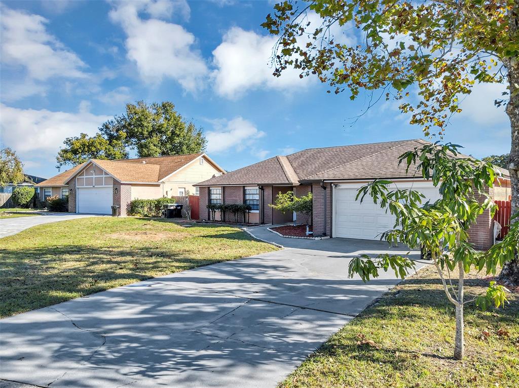 A single-story brick house with a concrete driveway and a front-facing garage — 6701 MERLIN COURT, ORLANDO, FL