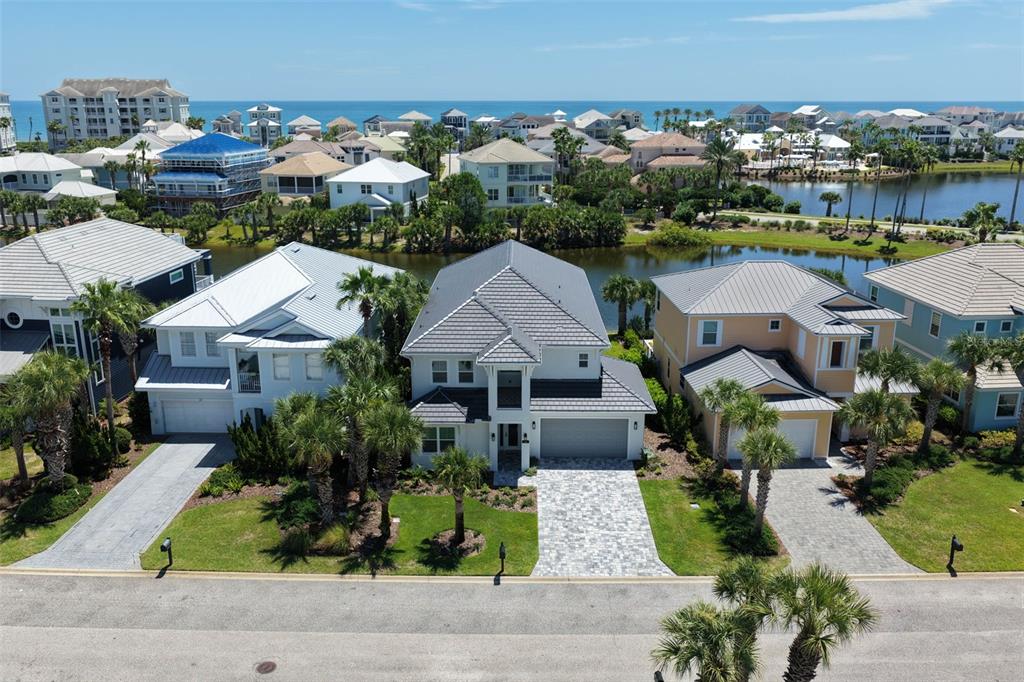 An aerial view shows a residential street with houses, palm trees, and a nearby lake — 18 CINNAMON BEACH WAY, PALM COAST, FL