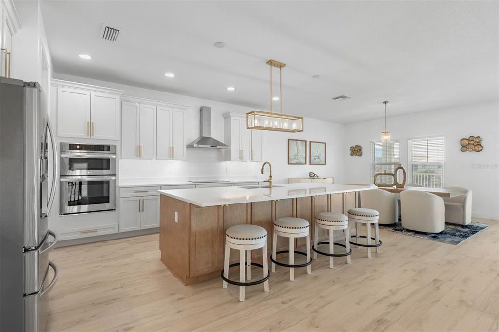 A modern kitchen features white cabinets, a wood-toned island with bar seating, and stainless appliances — 18 CINNAMON BEACH WAY, PALM COAST, FL
