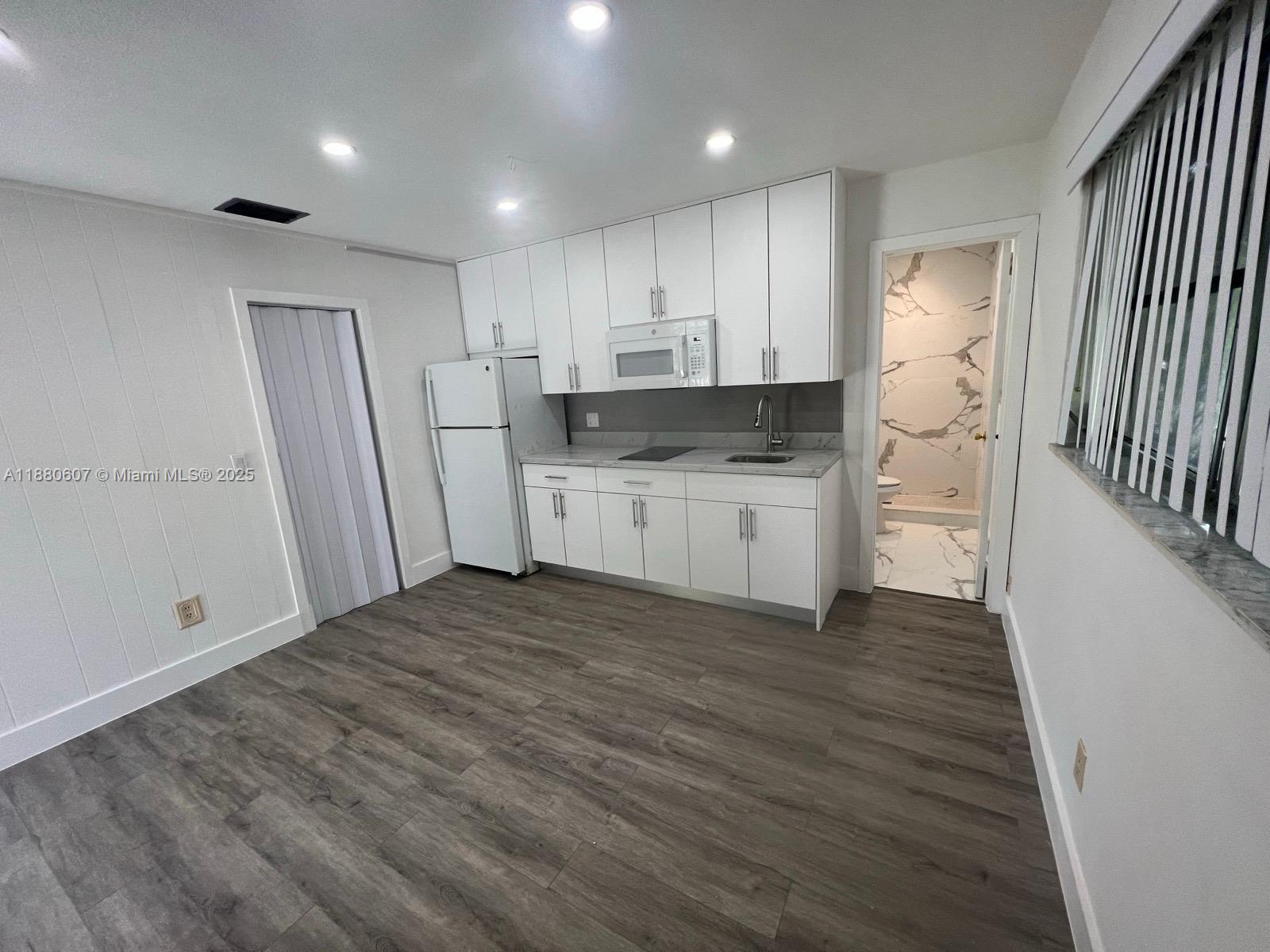 A small kitchen features white cabinets, stainless steel appliances, and wood-look flooring — 222 SW 8th St # C, Dania Beach FL 33004, DANIA BEACH, FL