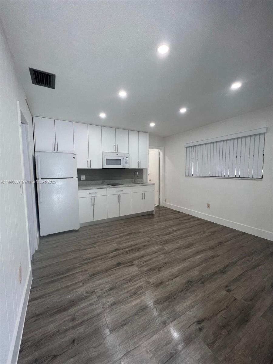 A kitchen features white cabinetry, a refrigerator, and wood-look flooring — 222 SW 8th St # C, Dania Beach FL 33004, DANIA BEACH, FL