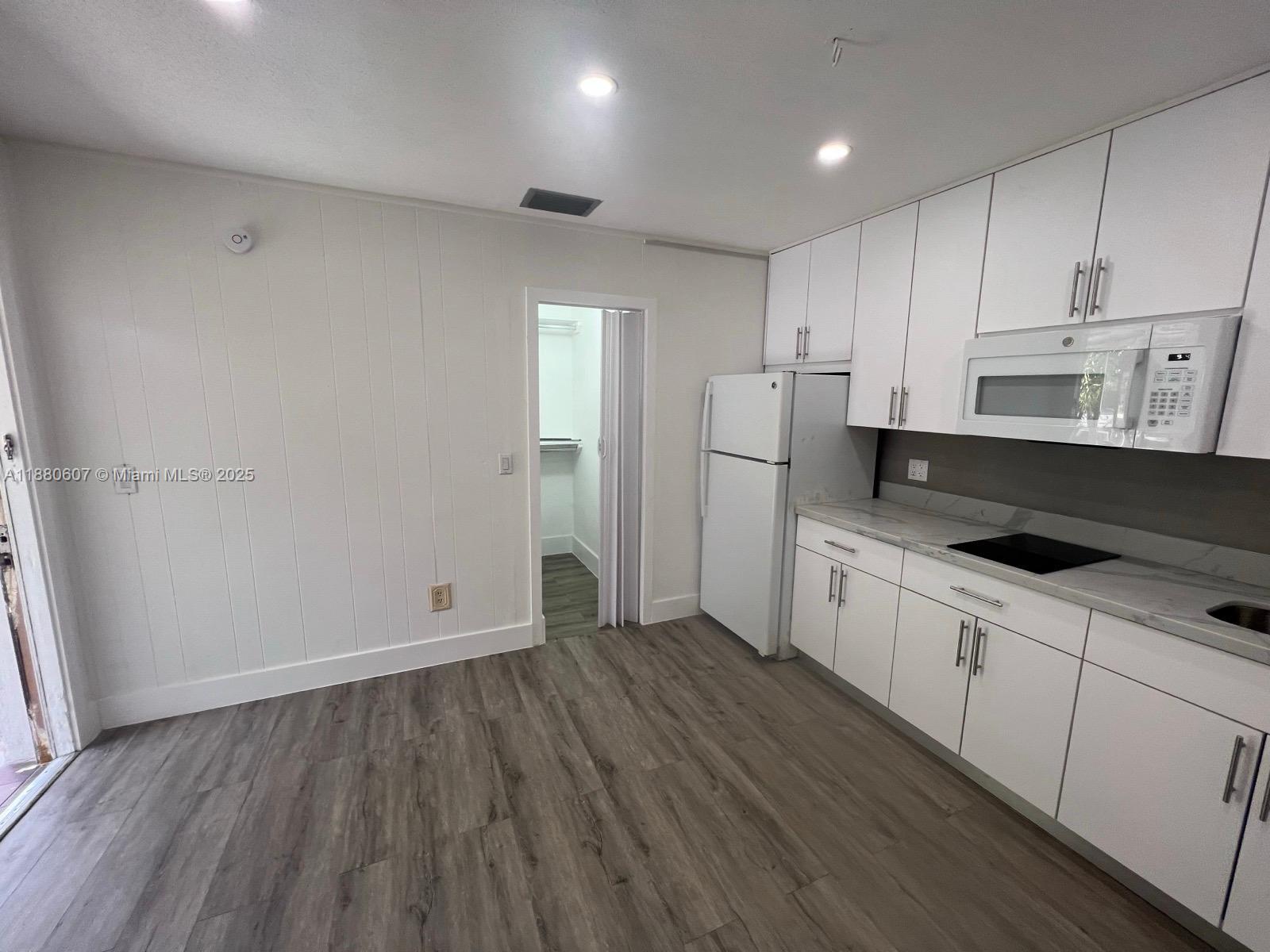 A kitchen features white cabinets, a white refrigerator, and wood-look flooring — 222 SW 8th St # C, Dania Beach FL 33004, DANIA BEACH, FL