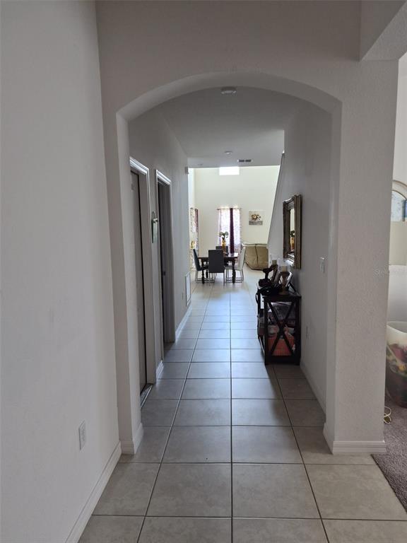 A tiled hallway leads through an arched entryway toward a dining area and living room — 1482 FLATWOOD STREET, ST CLOUD, FL