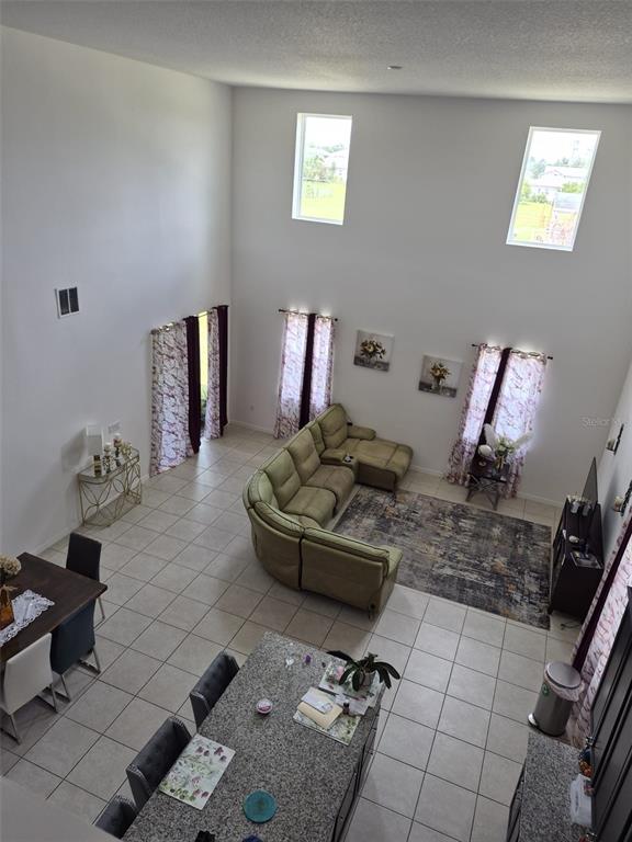 An elevated view of an open-concept living and dining area with high ceilings and tile floors — 1482 FLATWOOD STREET, ST CLOUD, FL