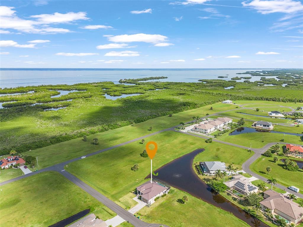 An aerial view shows a house with a pool situated near a canal and wetlands — 24050 BUNDY COURT, PUNTA GORDA, FL