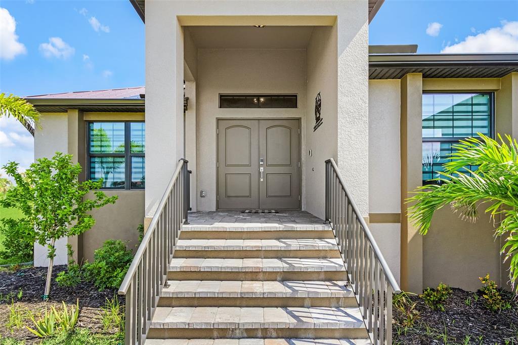 A front entrance with stone steps, metal railings, and double doors under a covered porch — 24050 BUNDY COURT, PUNTA GORDA, FL
