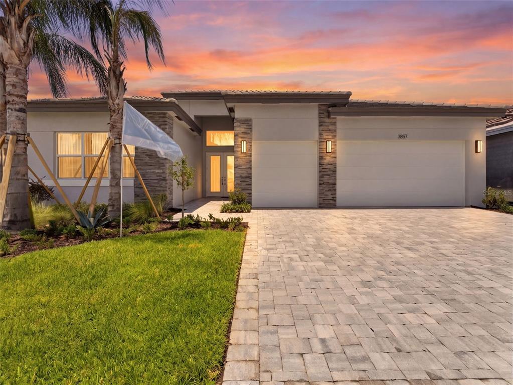 A modern single-story house with a stone-accented facade, a paved driveway, and a palm tree — 3857 CABERNET TERRACE, WESLEY CHAPEL, FL