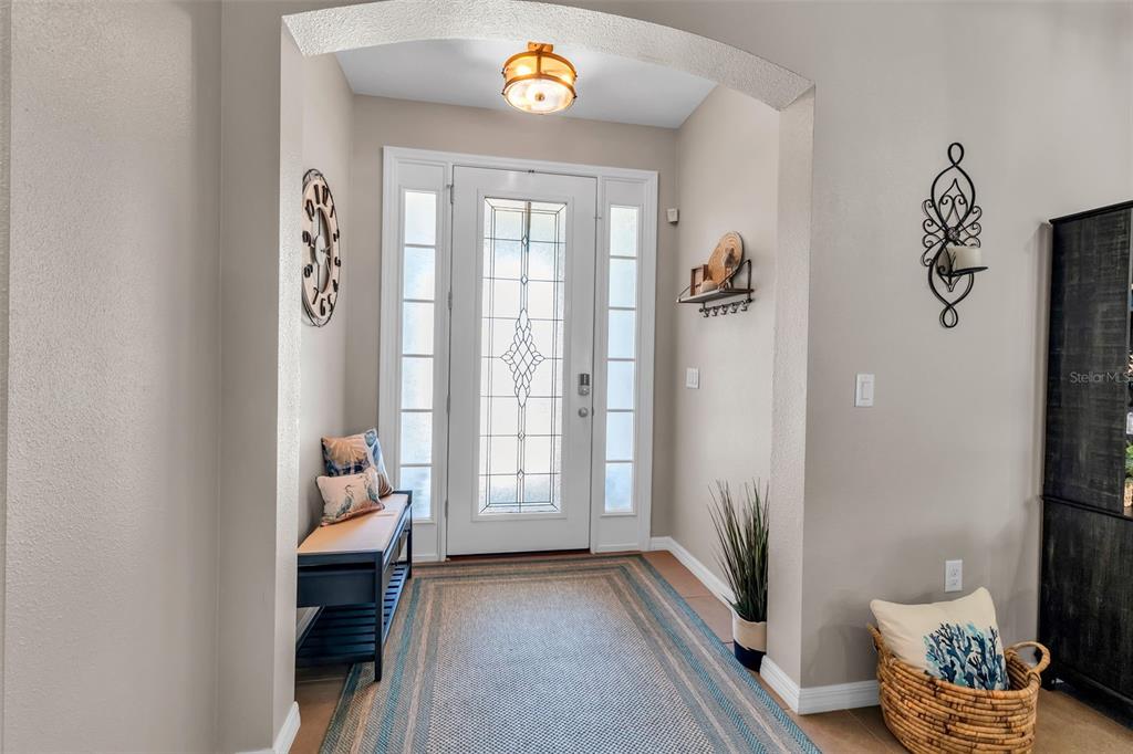 An entryway features a white front door with glass panels, a bench, and a rug — 13225 WATERLEAF GARDEN CIRCLE, RIVERVIEW, FL
