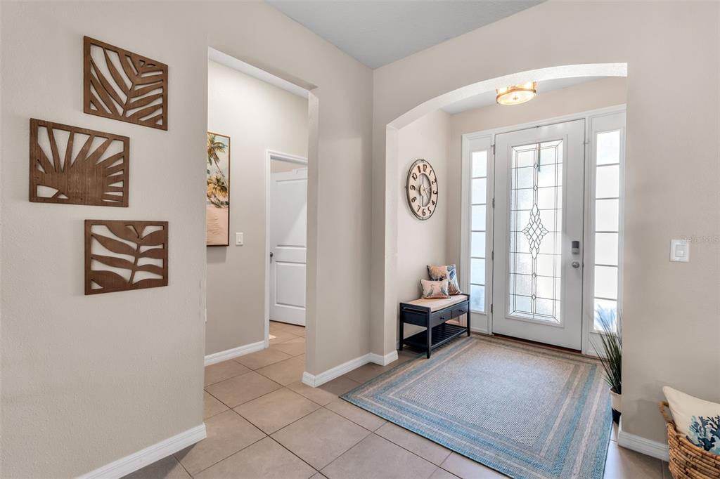 An entryway features tile flooring, a front door with glass panels, and a wall clock — 13225 WATERLEAF GARDEN CIRCLE, RIVERVIEW, FL