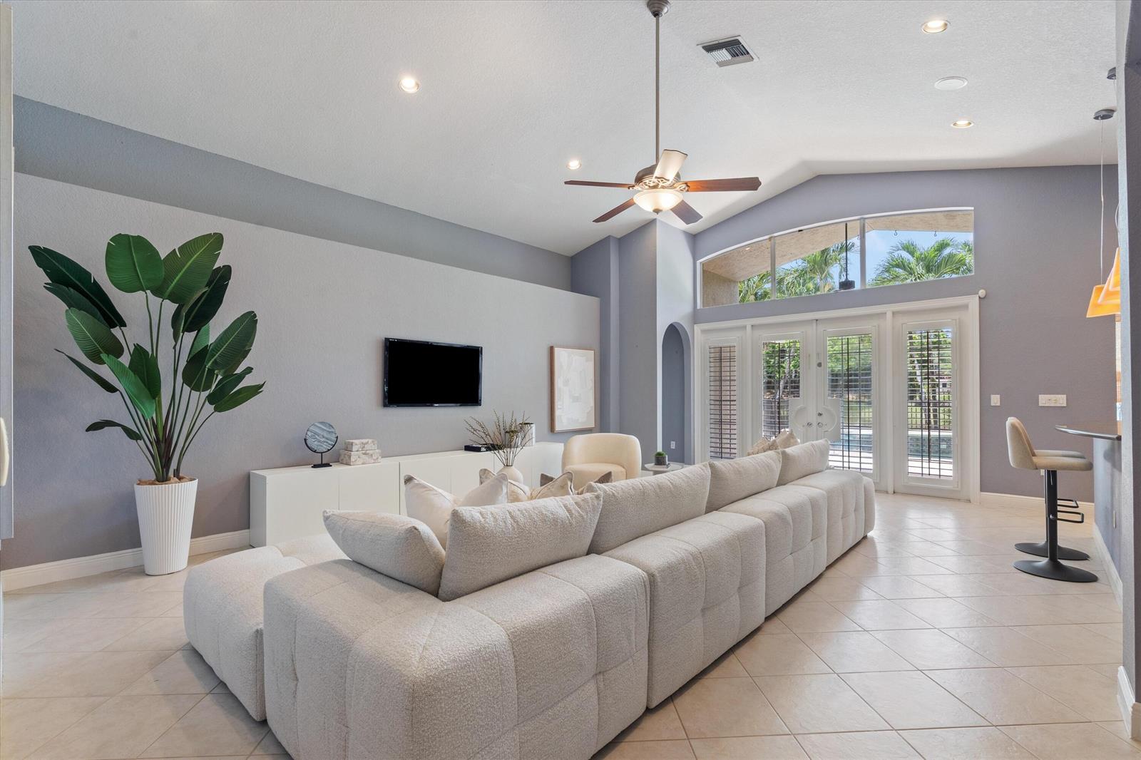 A living room features a large sectional sofa, a wall-mounted television, and vaulted ceilings — 19633 Estuary Drive, Boca Raton FL 33498, BOCA RATON, FL