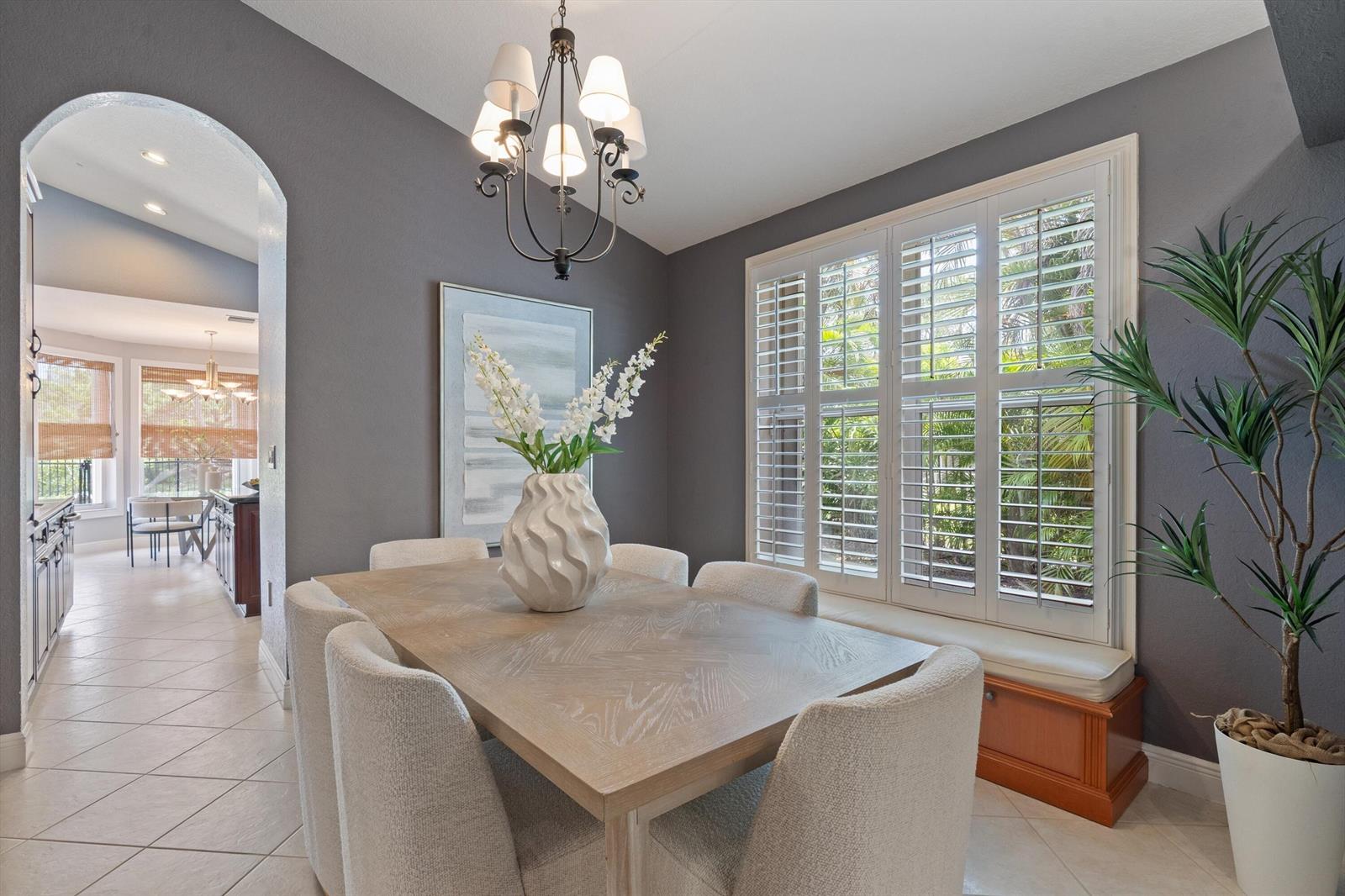 A dining room features a wooden table, upholstered chairs, dark gray walls, and plantation shutters — 19633 Estuary Drive, Boca Raton FL 33498, BOCA RATON, FL