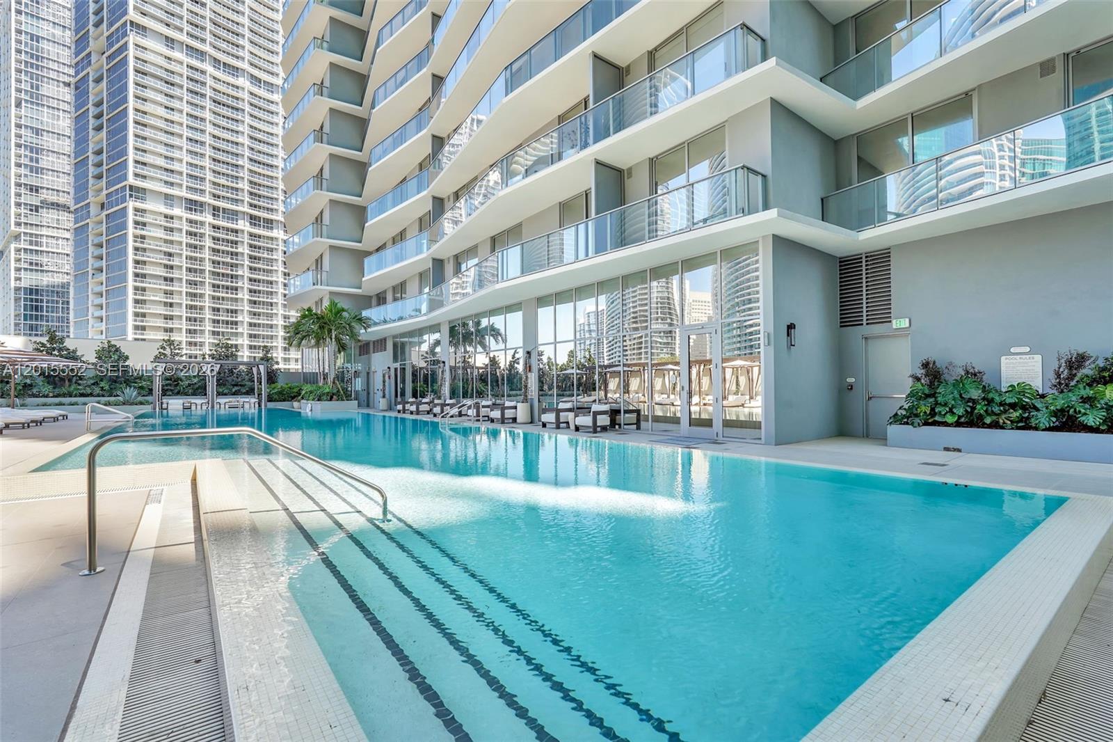 A living room features a grey sofa, white media console, and an open-concept kitchen — 77 SE 5th st # 1511, Miami FL 33131, MIAMI, FL