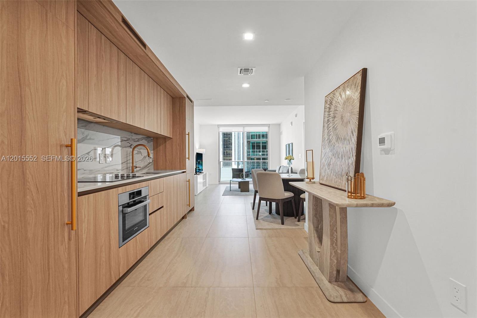 A modern living room features a gray sofa, round coffee table, and adjacent dining area — 77 SE 5th st # 1511, Miami FL 33131, MIAMI, FL