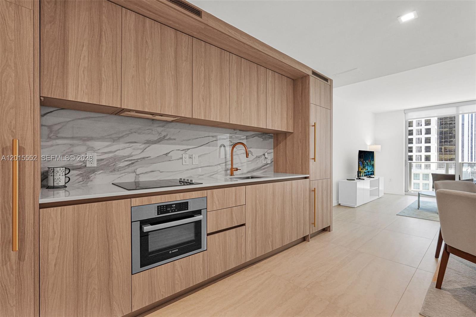 A modern living room features a gray sofa, a round coffee table, and floor-to-ceiling windows — 77 SE 5th st # 1511, Miami FL 33131, MIAMI, FL