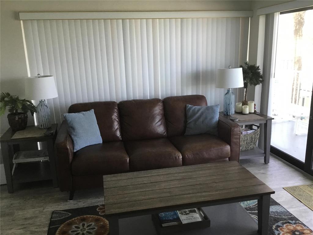 A living room features a brown leather sofa, two side tables with lamps, and a coffee table — 1571 S ATLANTIC AVENUE UNIT 212, NEW SMYRNA BEACH, FL