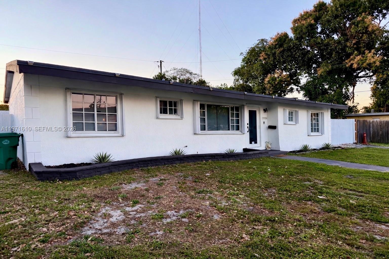 A single-story white house with a dark trim roof and a low stone planter wall — 19730 NW 3rd Ct, Miami Gardens FL 33169, MIAMI GARDENS, FL