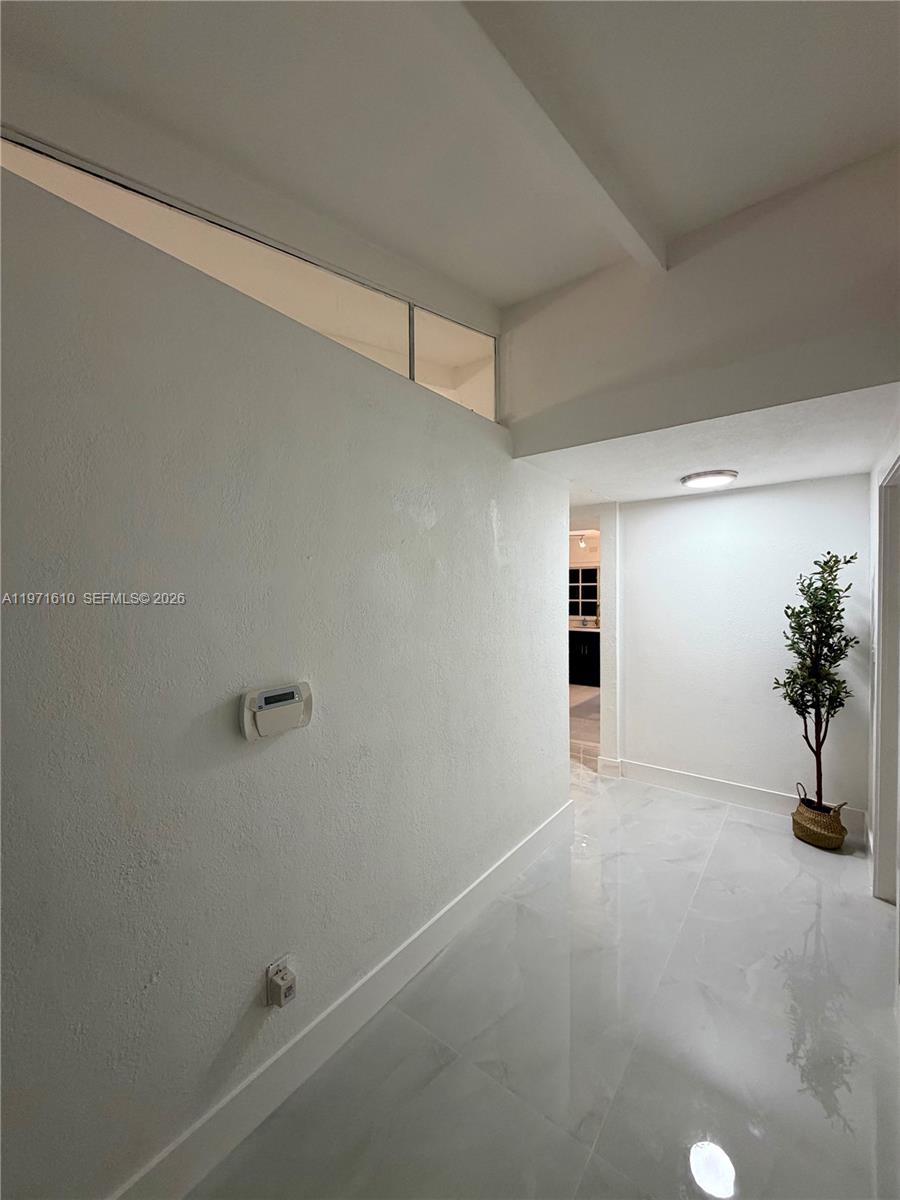 A bright hallway features white walls, glossy tile flooring, and a small decorative potted tree — 19730 NW 3rd Ct, Miami Gardens FL 33169, MIAMI GARDENS, FL