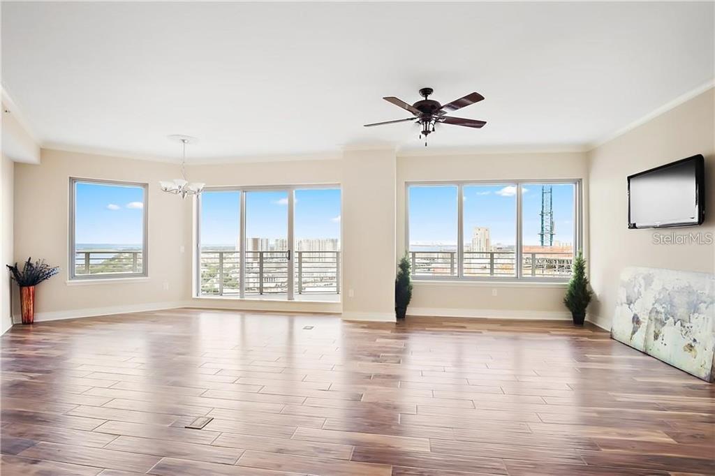 A spacious living area with wood-look tile flooring, a ceiling fan, and large floor-to-ceiling windows — 449 S 12TH STREET UNIT 1904, TAMPA, FL