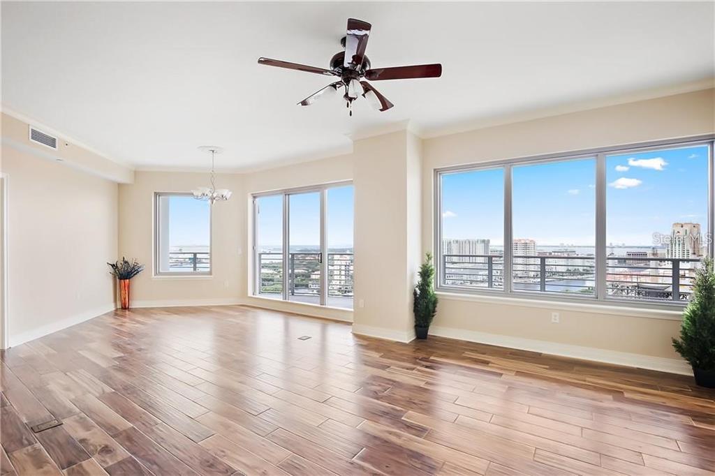 An empty living room with hardwood floors, a ceiling fan, and large windows overlooking water — 449 S 12TH STREET UNIT 1904, TAMPA, FL