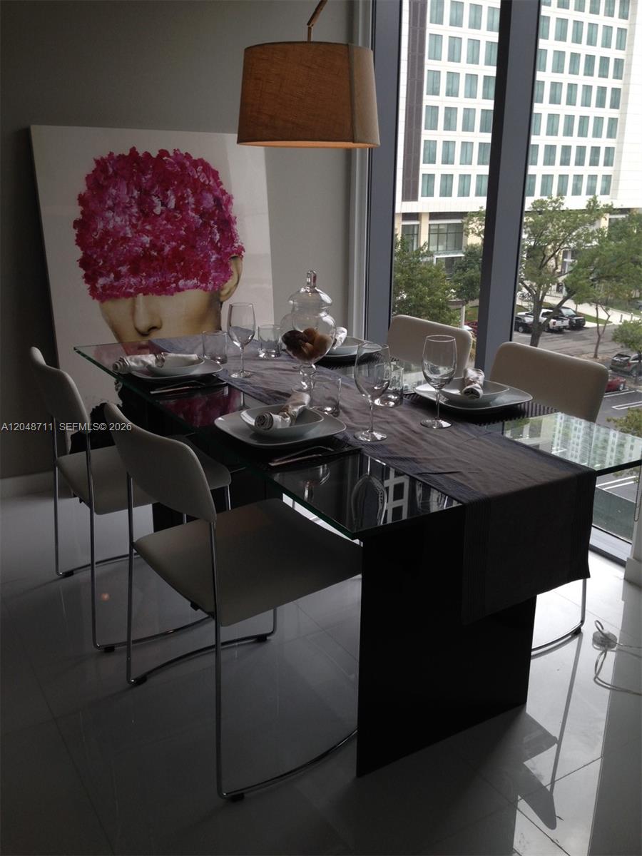 A modern dining room features a glass table, white chairs, and large abstract wall art — 31 SE 6 STREET # 603, Miami FL 33131, MIAMI, FL