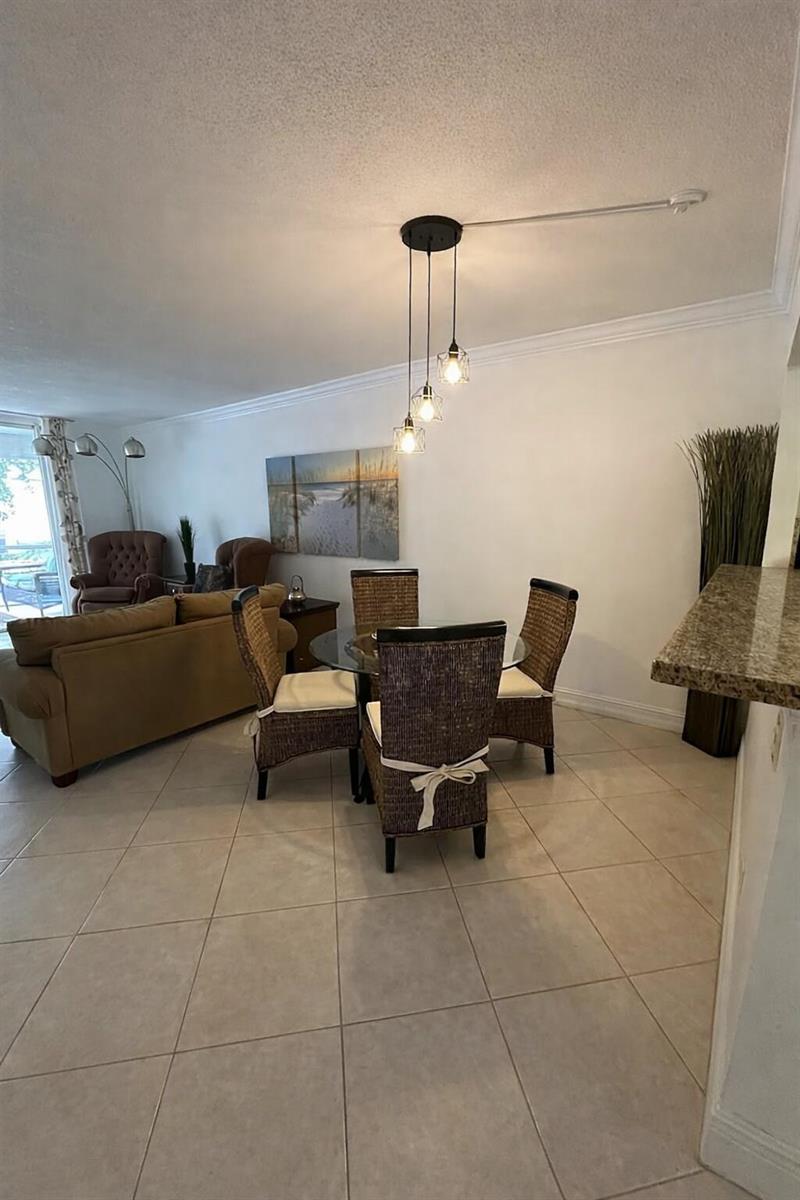 A dining area features a glass table, four wicker chairs, and a three-light pendant fixture — 400 SE 10th Street # 202, Deerfield Beach FL 33441, DEERFIELD BEACH, FL