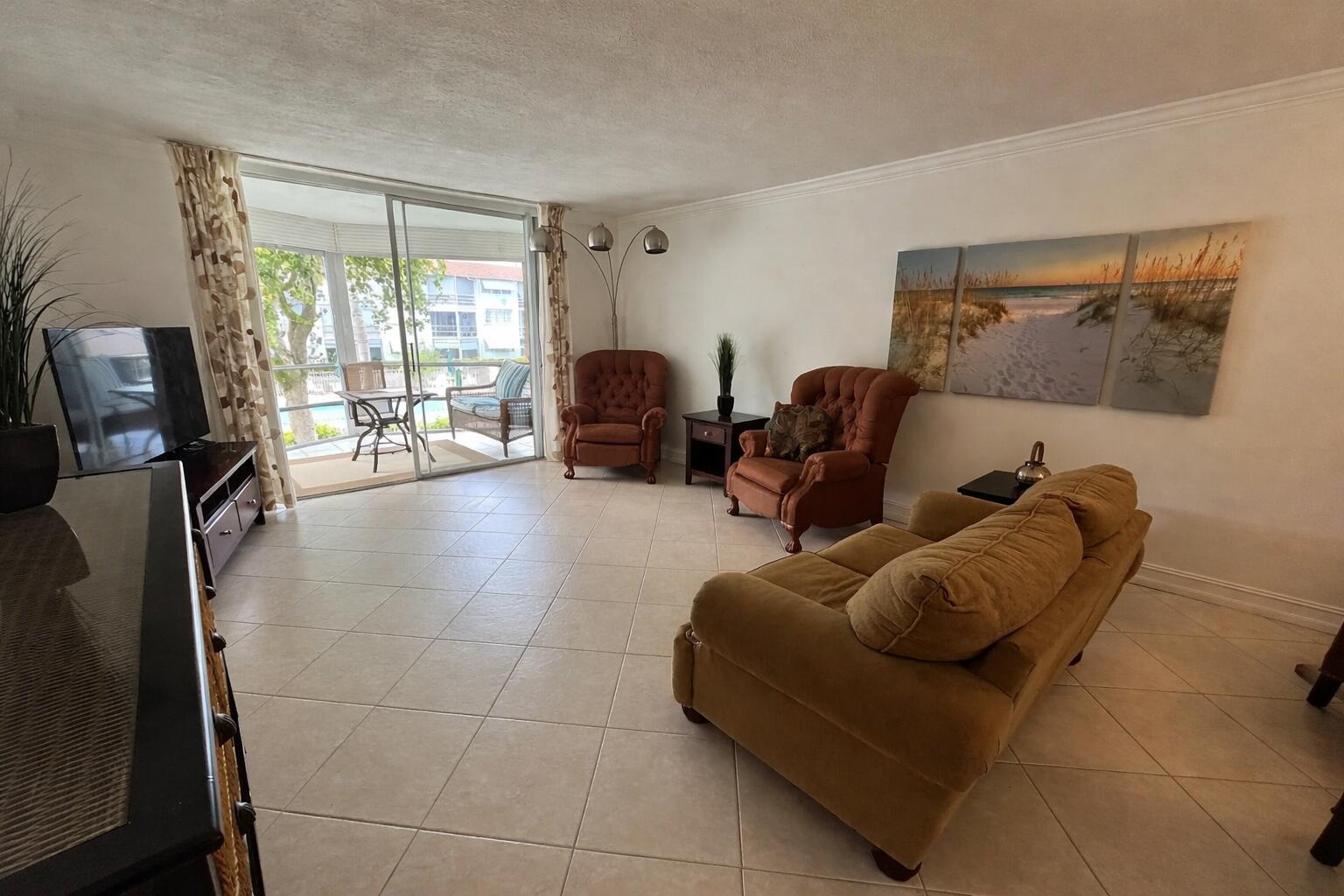 A living room with tile floors, a sofa, two armchairs, and a sliding glass door — 400 SE 10th Street # 202, Deerfield Beach FL 33441, DEERFIELD BEACH, FL