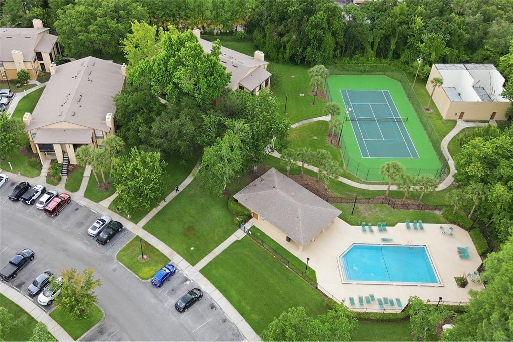 An aerial view shows apartment buildings, a swimming pool, a tennis court, and parking spaces — 4800 S SEMORAN BOULEVARD UNIT 107, ORLANDO, FL