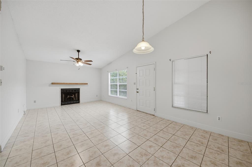A living room with tile flooring, a fireplace, a ceiling fan, and a front door — 4800 S SEMORAN BOULEVARD UNIT 107, ORLANDO, FL