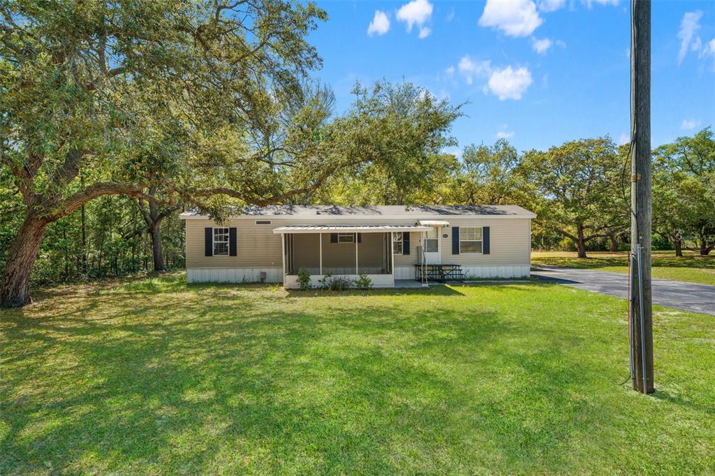A single-story manufactured home with a screened-in front porch sits on a grassy lot — 3345 BALLARD STREET, SPRING HILL, FL