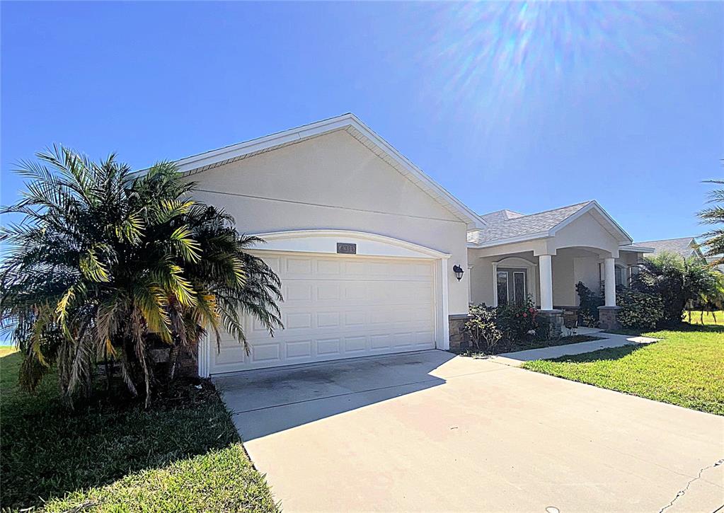 A single-story house with a two-car garage, light-colored stucco exterior, and a palm tree — 4311 MANDOLIN BOULEVARD, WINTER HAVEN, FL