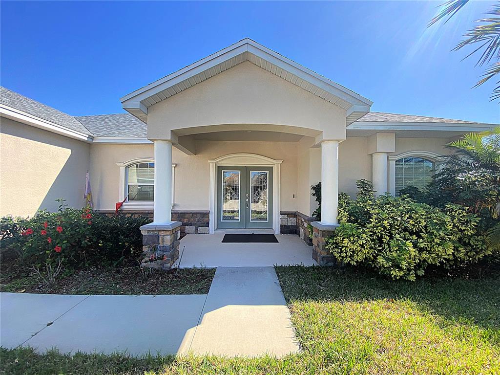 The exterior of a house features a covered entryway with white columns and double doors — 4311 MANDOLIN BOULEVARD, WINTER HAVEN, FL