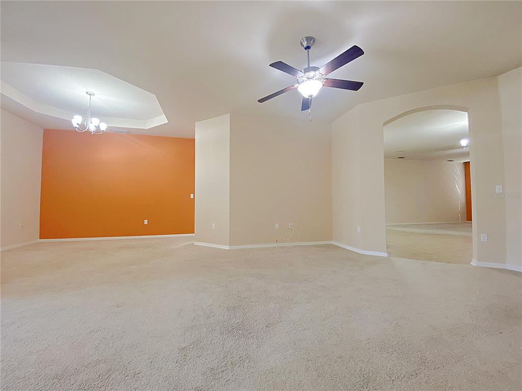 An empty room with beige carpet, an orange accent wall, and a ceiling fan — 4311 MANDOLIN BOULEVARD, WINTER HAVEN, FL