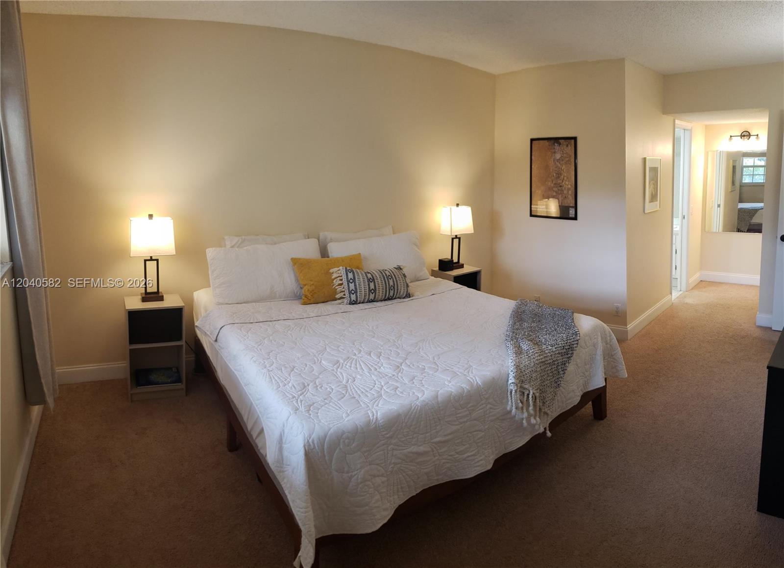 A bedroom features a queen bed with white bedding, two nightstands, and beige carpeting — 550 Oaks Ln # 202, Pompano Beach FL 33069, POMPANO BEACH, FL