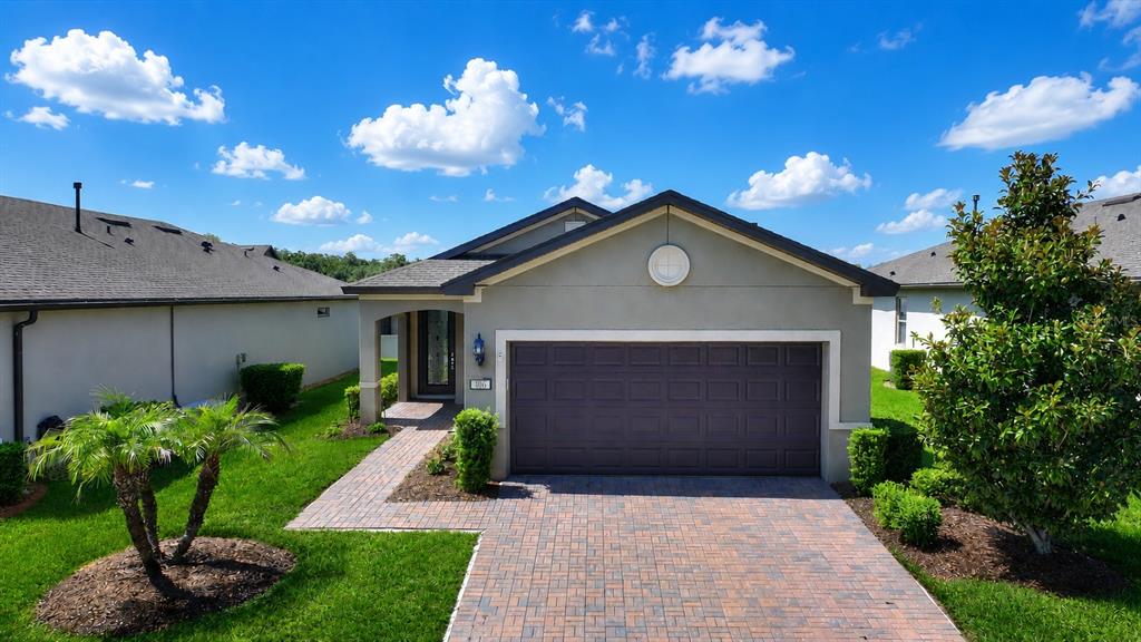 A single-story house with a paved driveway, a two-car garage, and a landscaped front yard — 406 TORTOSA COURT, DAVENPORT, FL