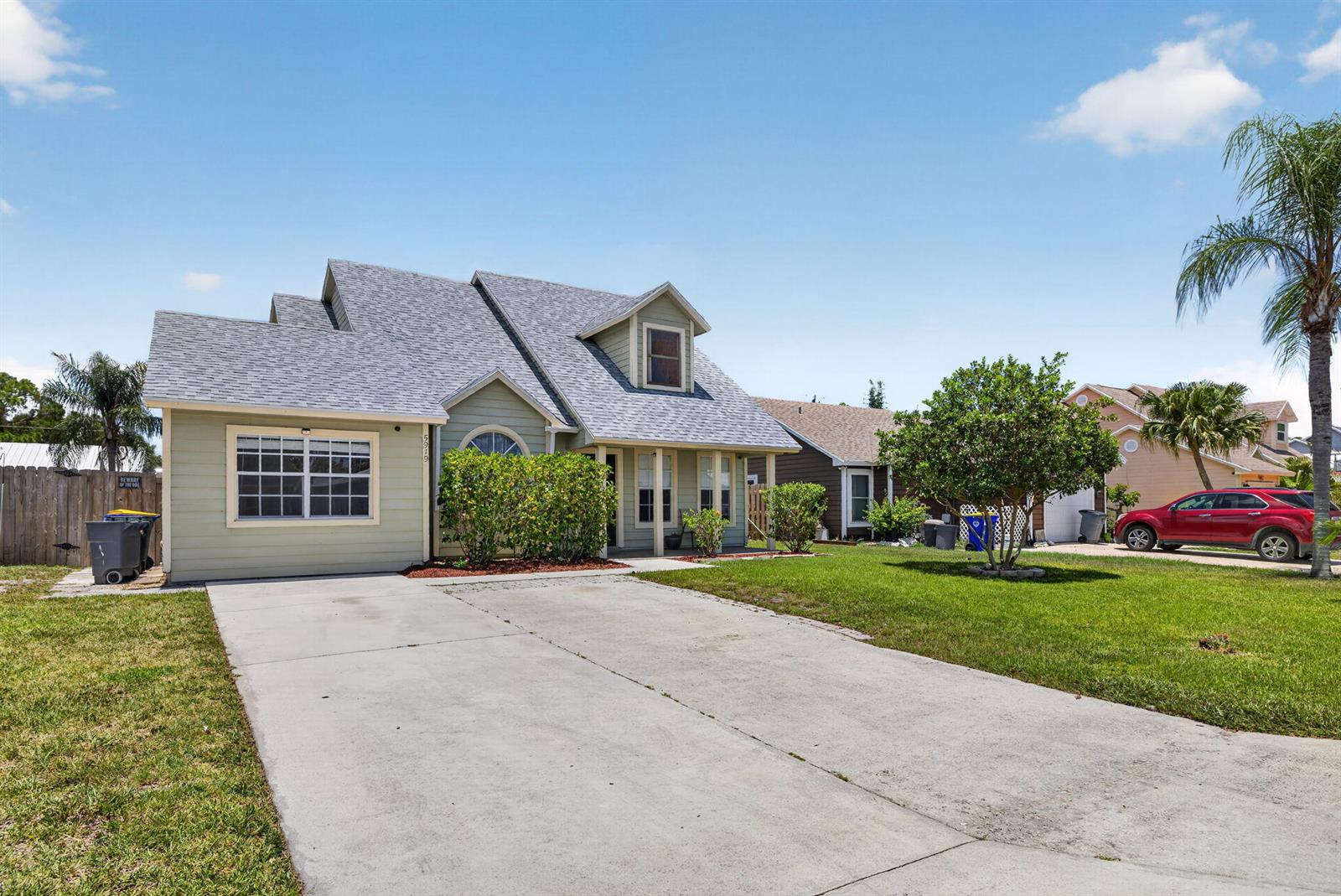 A light green two-story house with a concrete driveway and a front yard — 5919 SE Pine Drive, Stuart FL 34997, STUART, FL