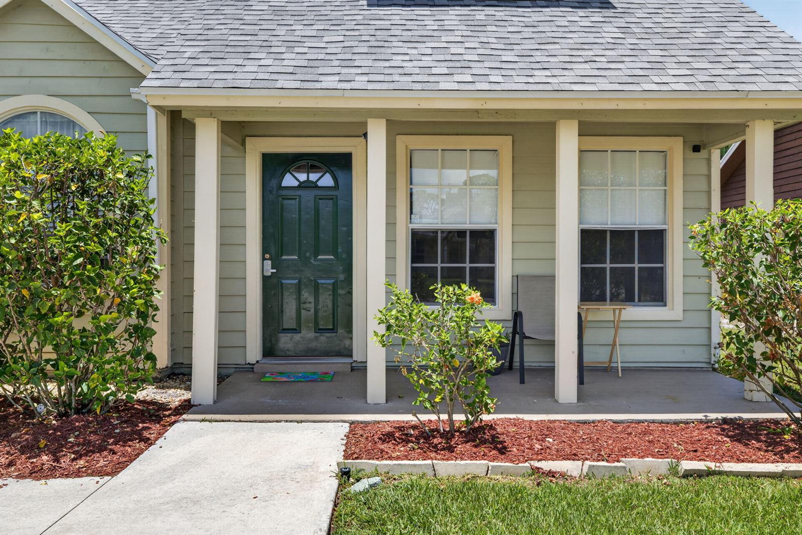 A light green house exterior features a dark green front door and a covered porch — 5919 SE Pine Drive, Stuart FL 34997, STUART, FL