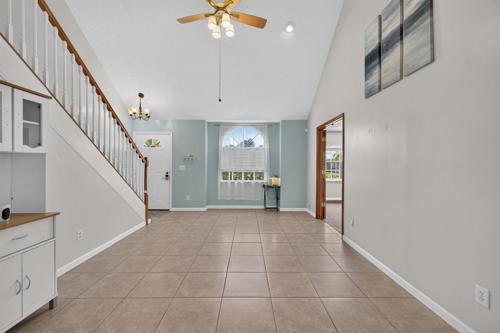 An entryway with tiled floors, a staircase, a vaulted ceiling, and a light blue wall — 5919 SE Pine Drive, Stuart FL 34997, STUART, FL