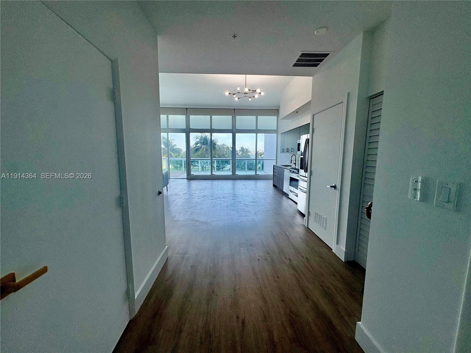 A hallway leads into an open-concept living area with wood floors and floor-to-ceiling windows — 1800 N Bayshore Dr # 306, Miami FL 33132, MIAMI, FL