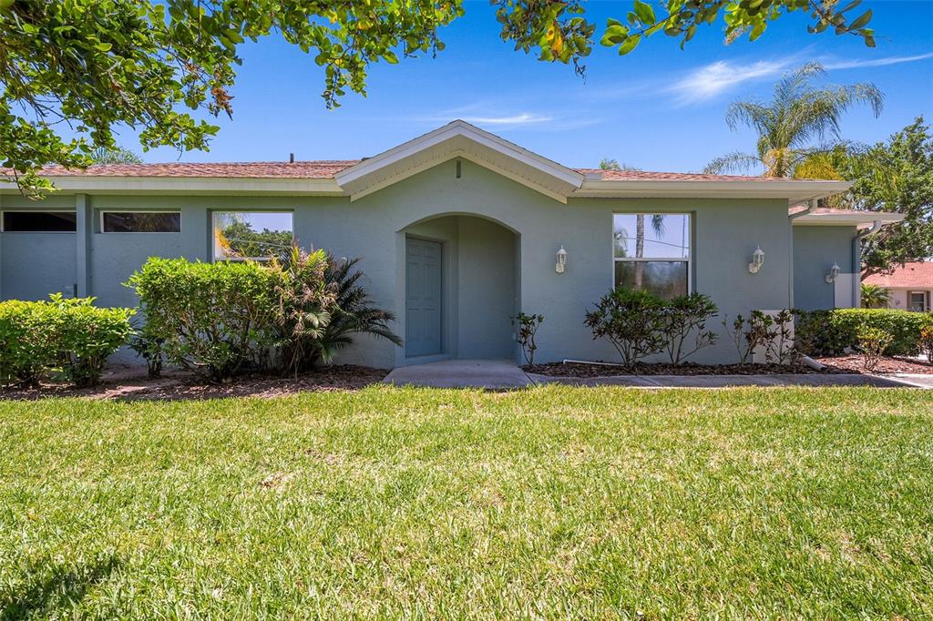 A single-story house with light green stucco siding, a front entryway, and a grassy lawn — 1204 HUNTINGTON GREENS DRIVE UNIT 1204, SUN CITY CENTER, FL