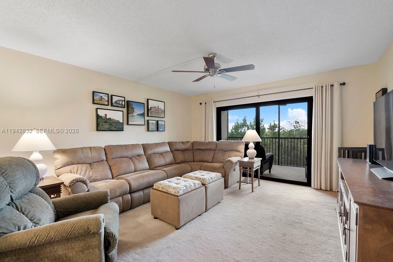 A living room features a large sectional sofa, a ceiling fan, and a sliding glass door — 2200 S Cypress Bend Dr # 406, Pompano Beach FL 33069, POMPANO BEACH, FL