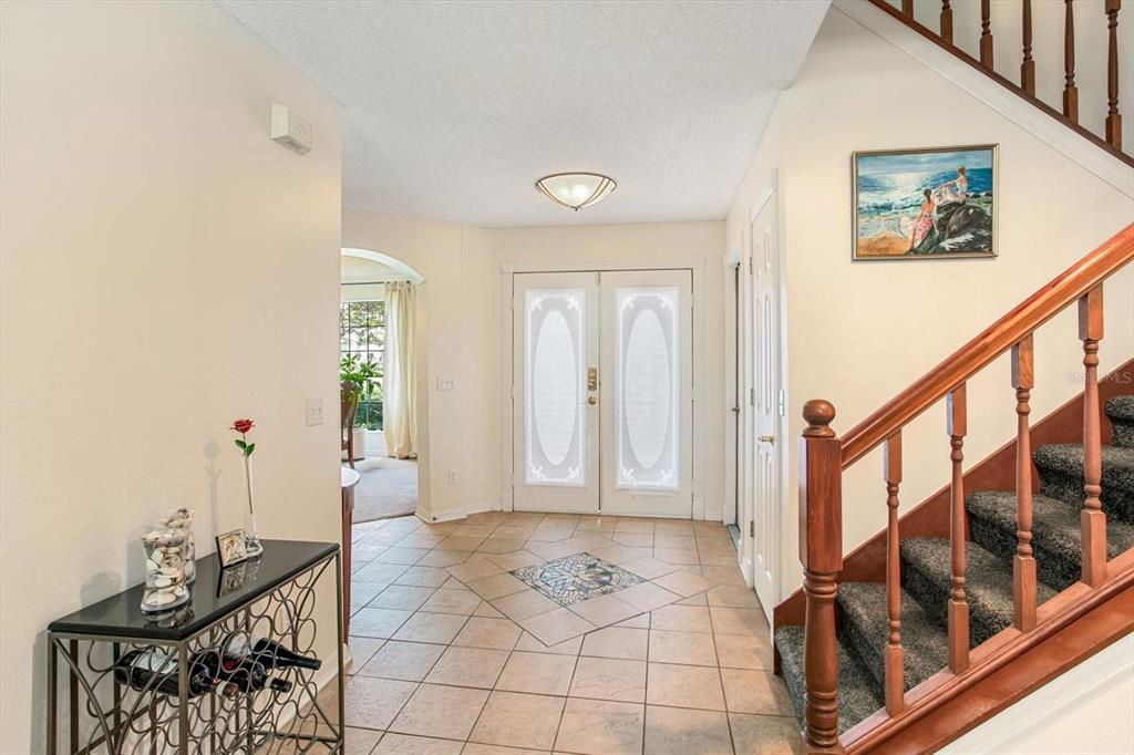 A tiled foyer features a staircase with a wooden railing and a double front door — 3920 RUNNING WATER DRIVE, ORLANDO, FL