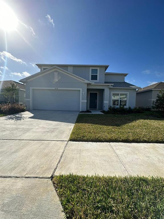 A two-story house with a light gray exterior, a two-car garage, and a concrete driveway — 5656 COSTA BLANCA WAY, DAVENPORT, FL