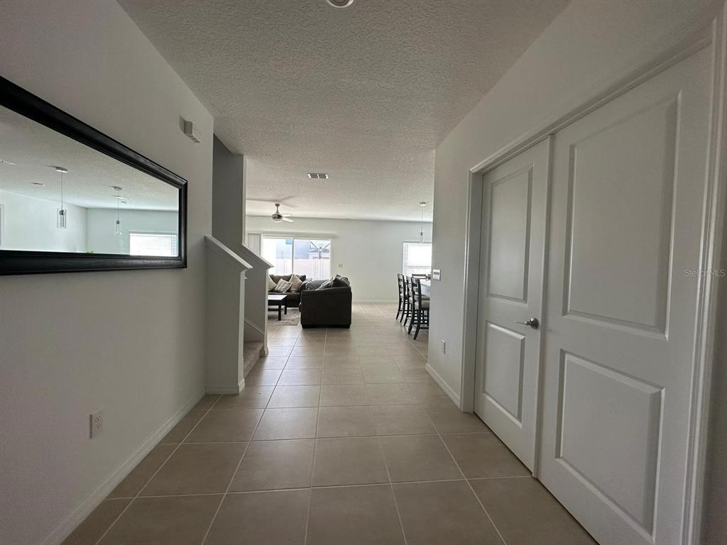 A tiled entryway leads to an open-concept living area with a staircase and closet — 5656 COSTA BLANCA WAY, DAVENPORT, FL